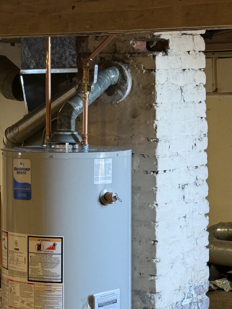 Bradford White residential water heater with copper piping and vent in a basement