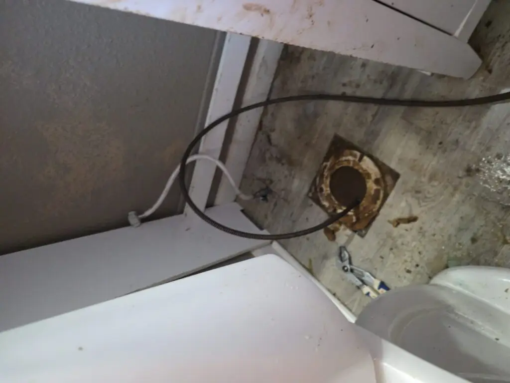 Drain snake cable inserted into a toilet flange during residential drain cleaning