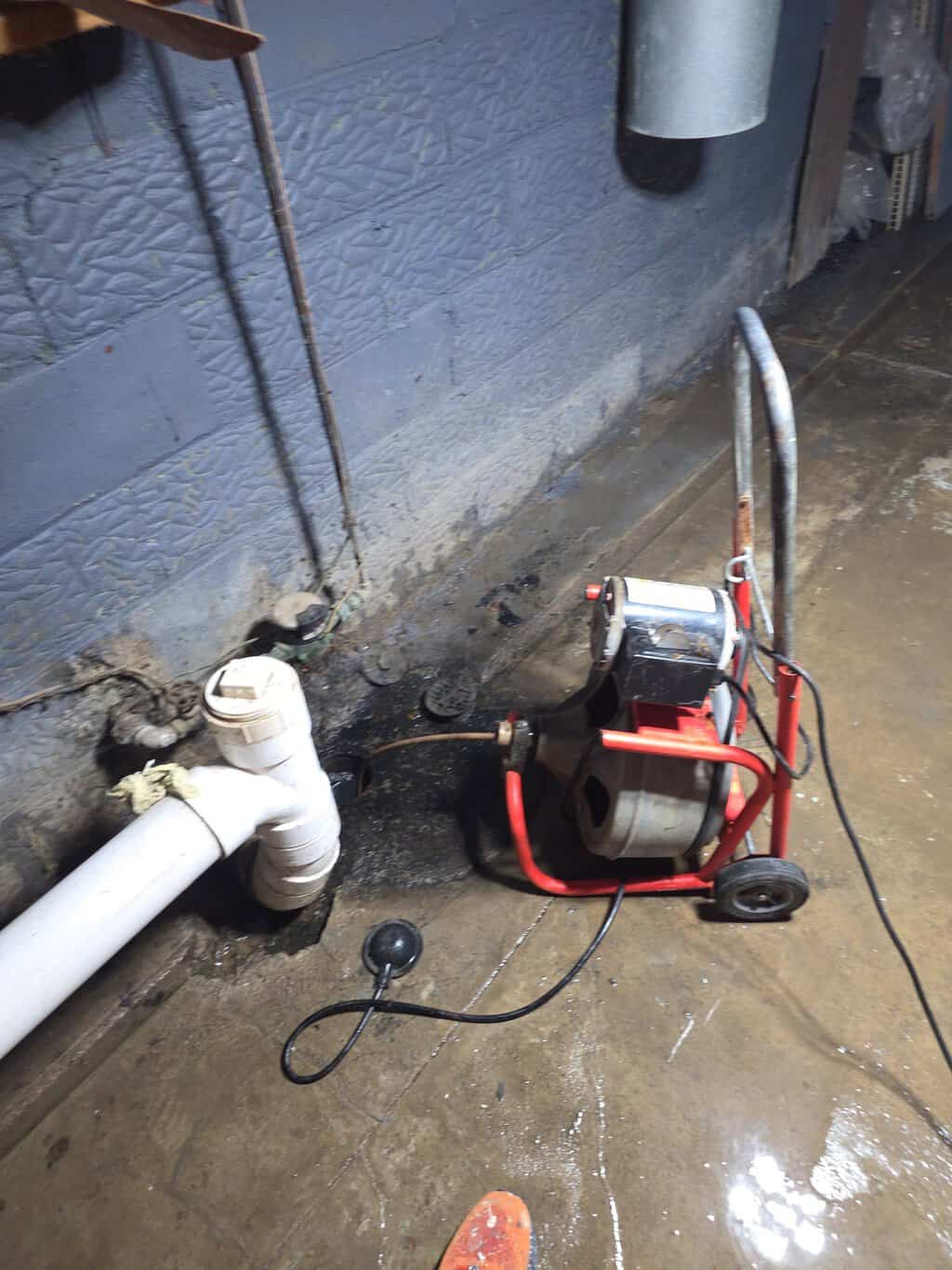 Drain cleaning machine working on underground pipes at a construction site.