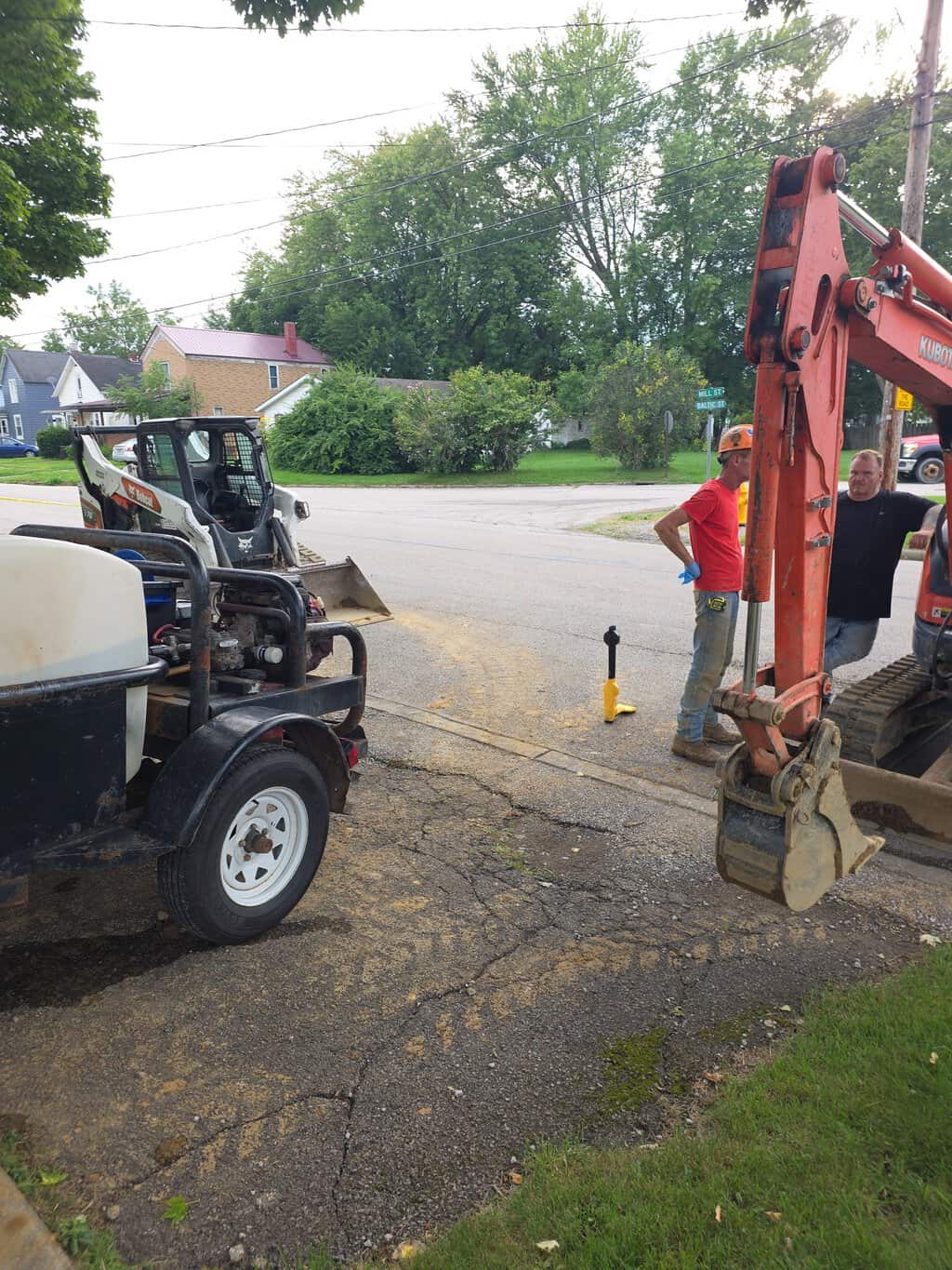 Kubota excavator, skid steer, and tank trailer with crew at a residential jobsite