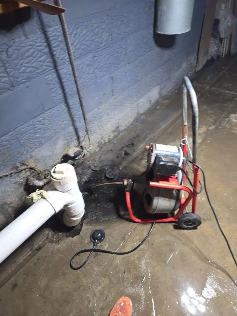 Electric drain cleaning machine feeding cable into a basement floor drain