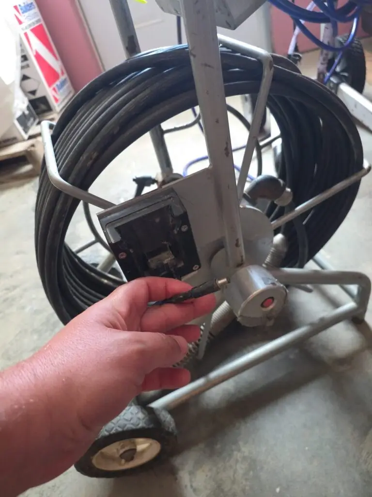 Technician connecting power to a wheeled sewer camera inspection cable reel