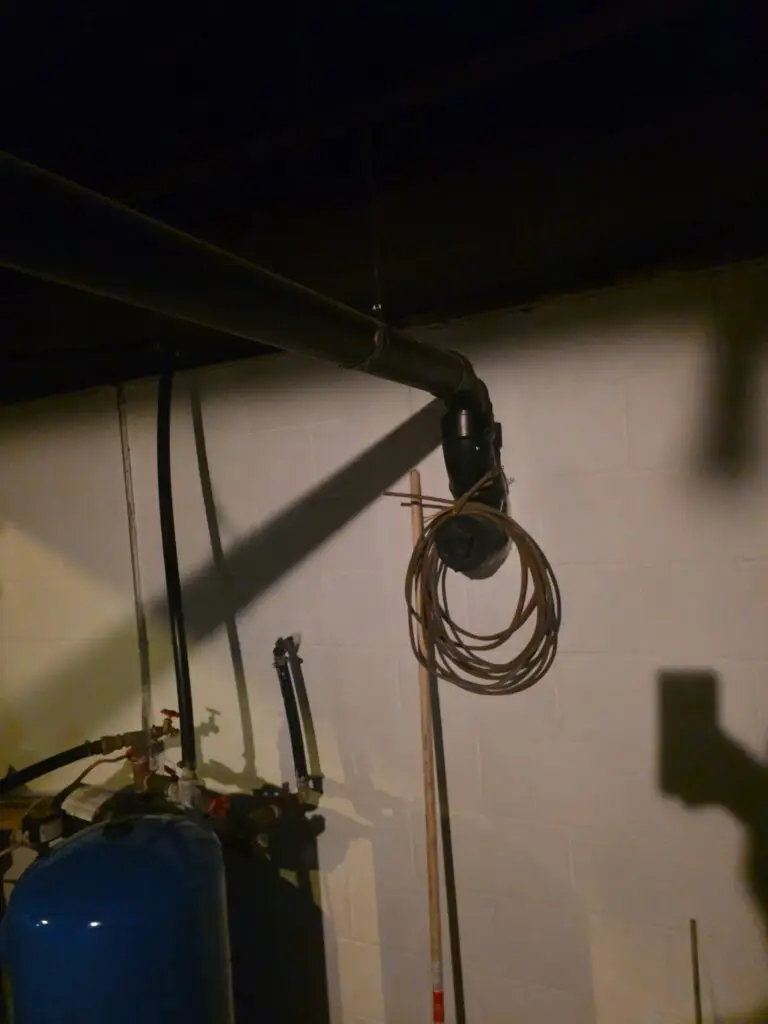 Basement plumbing with drain cleanout piping and a blue well pressure tank