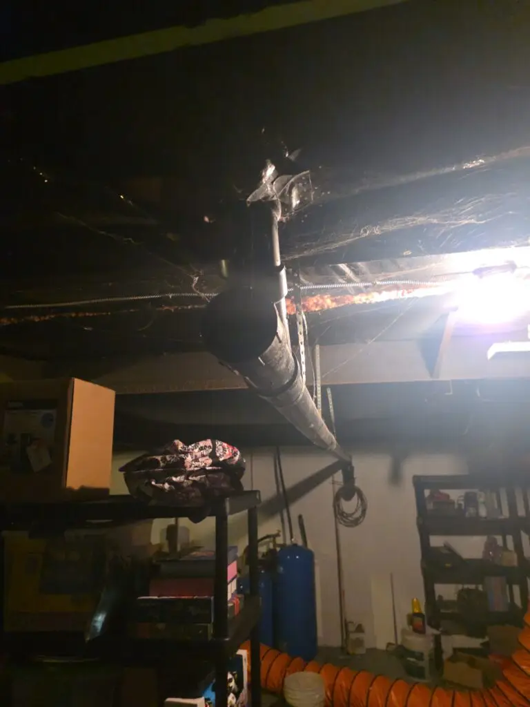 Large black main drain pipe running through a residential basement ceiling
