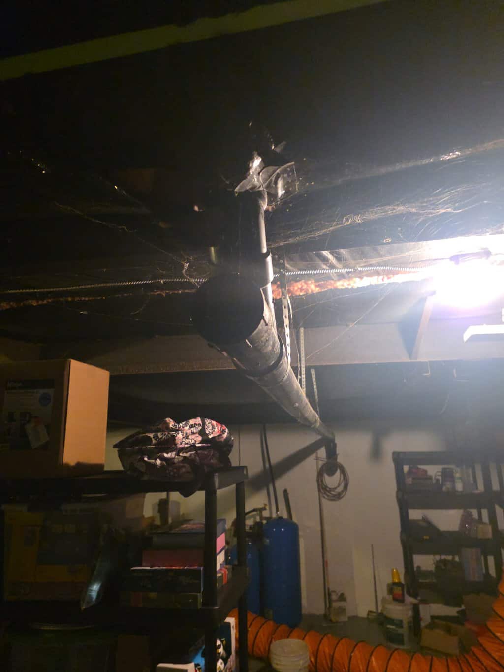 Large black main drain pipe running through a residential basement ceiling