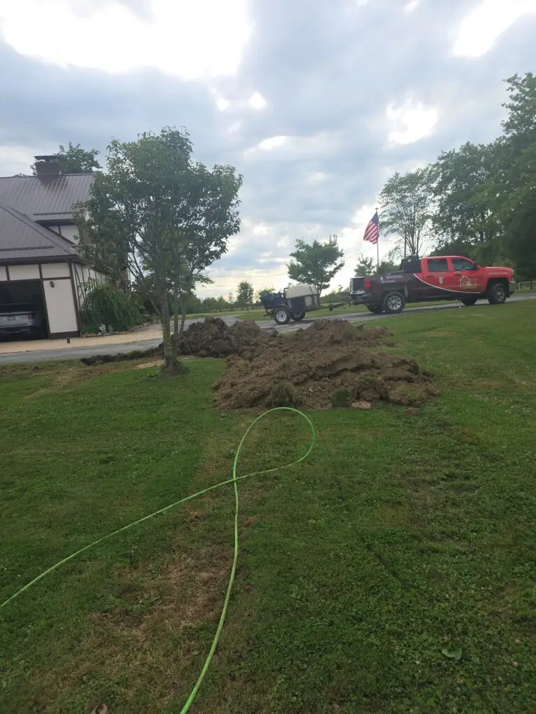 S&K Drain Cleaning service truck and tank trailer beside a residential yard excavation